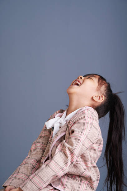 Happy small girl on the grey background in the studio.