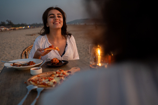 Two women friends have a casual dinner at disk on Morjim beach in Goa.