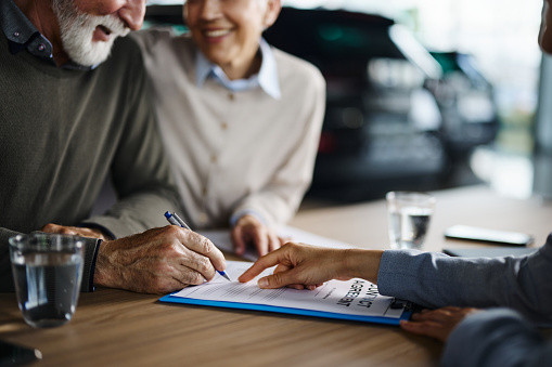 Close up of unrecognizable couple signing a contract on a meeting with agent.