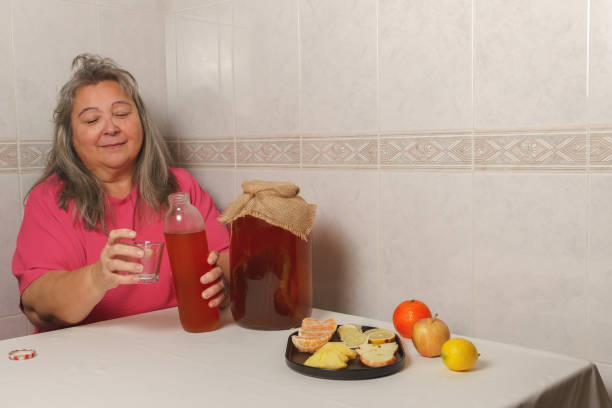 コンブチャ茶を果物で満たす女性 - fungus science bottle glass ストックフォトと画像