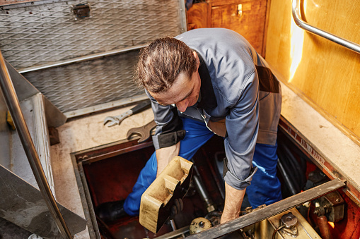 Portrait of male worker repairing boat engine in docks, copy space
