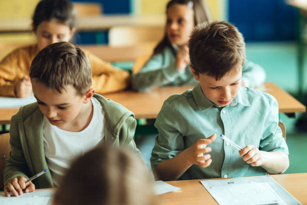 istock Schoolchildren writing in workbook at desk in classroom 1455915111