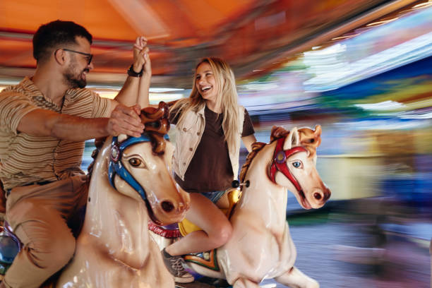 istock Happy couple having fun on merry-go-round carousel at amusement park. 1455915230