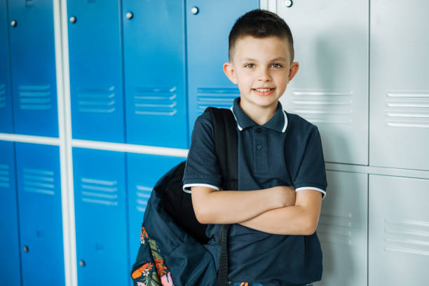 istock elementary schoolboy standing in front of lockers in school corridor 1455915455