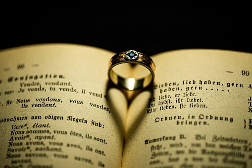 A top view of a ring on a book with a heart shape shadow