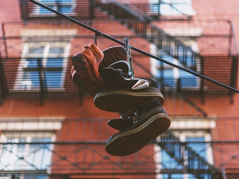 A selective focus shot of a few pairs of shoes hanging to dry outdoors with building in background