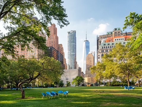 A scenic view of empty blue chairs in green Battery Park in New York City, United States.