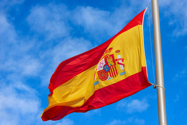 istock Spanish Flag Blowing in the Wind against a Blue Sky with Clouds 1455920728