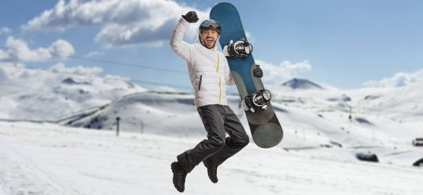 istock Happy man with a snowboard jumping and gesturing happiness on a mountain 1455922517