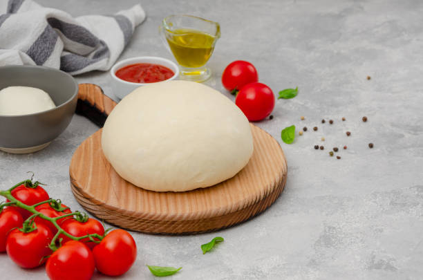 istock Fresh pizza dough with tomato sauce, mozzarella, tomatoes and basil leaves on a gray concrete background. Italian cuisine. Copy space. 1455923233