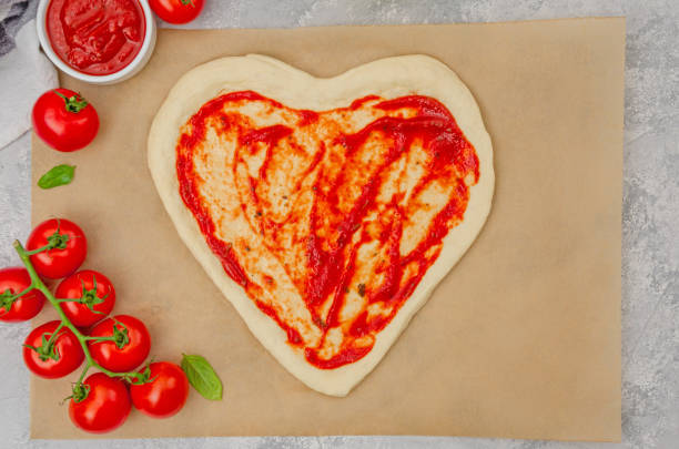 istock Pizza Margherita shaped heart with cherry tomatoes, mozzarella and basil on a gray concrete background. Food concept for Valentine's Day. Copy space. 1455923238