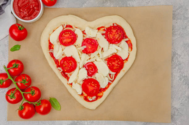 istock Pizza Margherita shaped heart with cherry tomatoes, mozzarella and basil on a gray concrete background. Food concept for Valentine's Day. Copy space. 1455923240