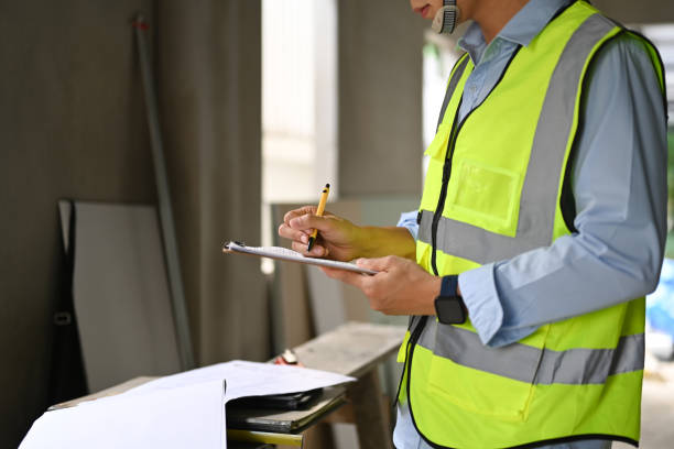 istock Cropped shot of engineer in reflective vest working on blueprints in construction site. 1455923376