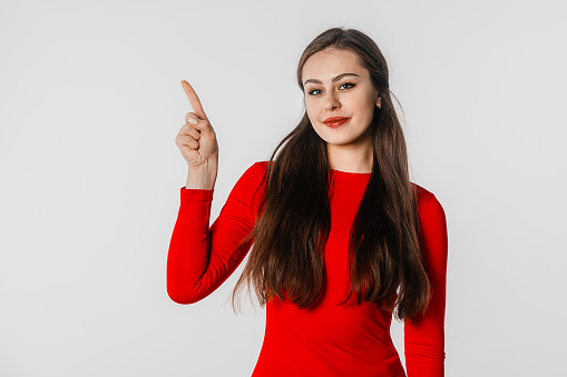Happy young woman pointing finger aside, showing amazing news, promo banner, offer. Portrait of student, secretary, girl, female over white studio background