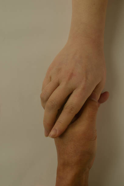 Medium close up of young adult couple holding each other hands, focus on hands