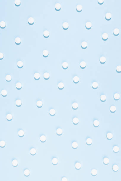 оздоровительные и аптечные средства для профилактики и терафии заболеваний и фона болезни - белые таблетки рисунок на пастельно-синем цвет - vitamin pill vertical high key photographic effects стоковые фото и изображения
