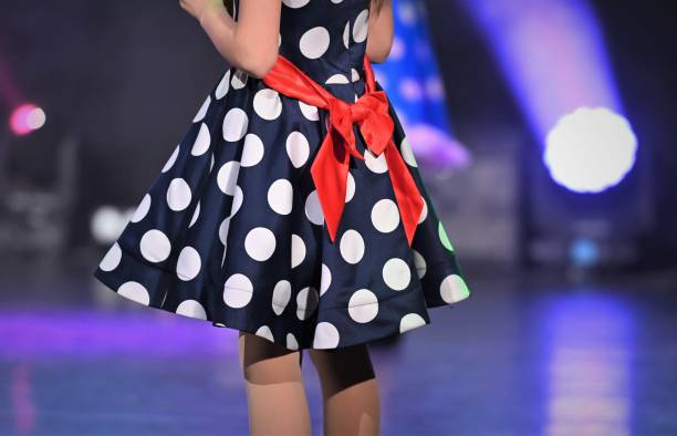 ステージ上の子供の背中に大きな水玉と赤いリボンが付いたドレス - polka dot ストックフォトと画像