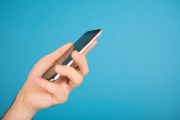 istock Closeup of a hand holding a phone on a blue background 1455930044