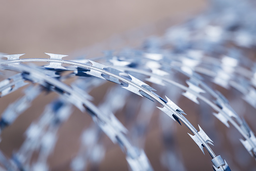 A closeup shot of barbed wire with cloudy sky in the background