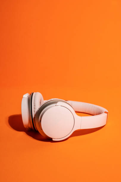 istock Wireless headphones on an orange background, modern and minimal style. 1455931332