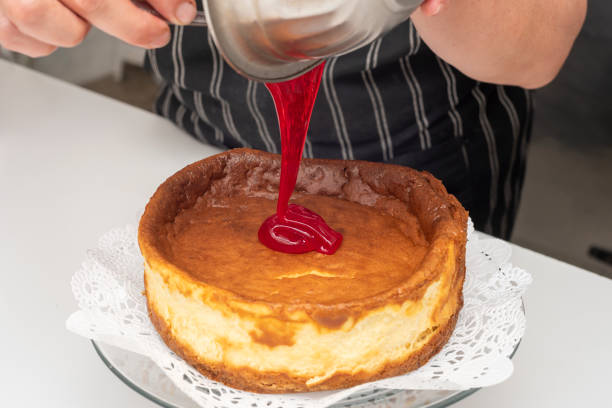 istock Pastry chef decorating the cheesecake with red jam 1455933349