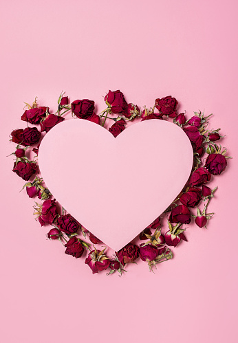 Heart with dry rose flowers on a pink background. Flowers in the shape of a heart. Postcard for March 8, Valentine's Day, Women's Day.
