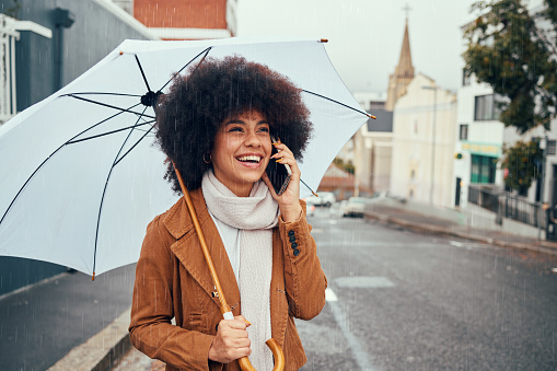 Phone call communication, rain and girl with umbrella talking, discussion or speaking about London city weather. Mobile conversation, winter storm or happy black woman on 5g network call with contact