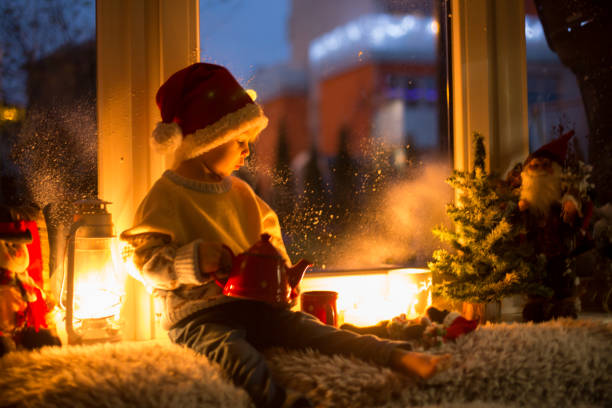 istock Cute child, sitting on a window, looking outdoors for Santa Claus 1455937845