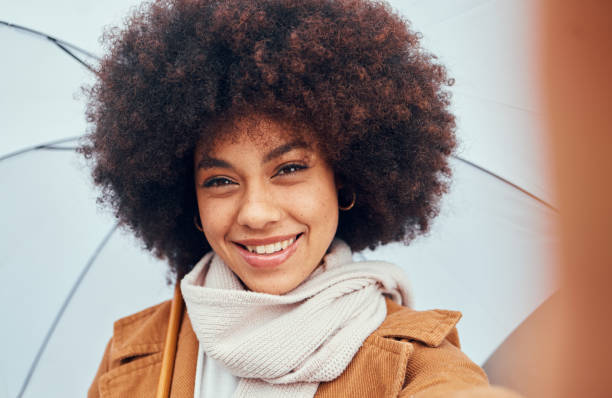 femme, selfie gros plan et parapluie sous la pluie, l’eau ou la bruine en portrait, bonheur et sourire. femme noire, cheveux ou afro beauté avec parasol pour se protéger des éléments, du climat ou de la tempête tout en étant heureux - rain women umbrella parasol photos et images de collection