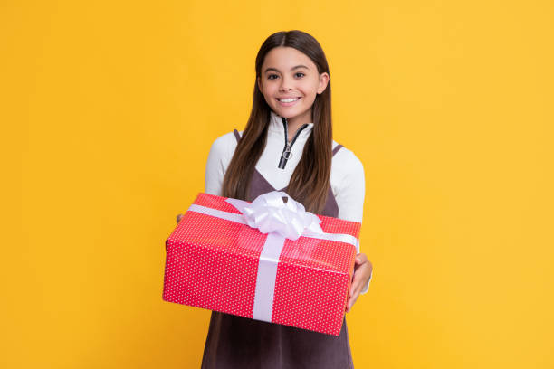 istock smiling child with present box on yellow background 1455939590