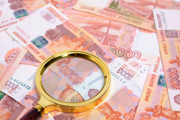 istock Magnifying magnifier against background Russian rubles with face value five thousand. 1455941456