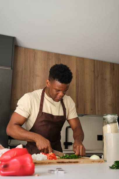 istock Young african man cutting celery to prepare chicken recipe. 1455941918