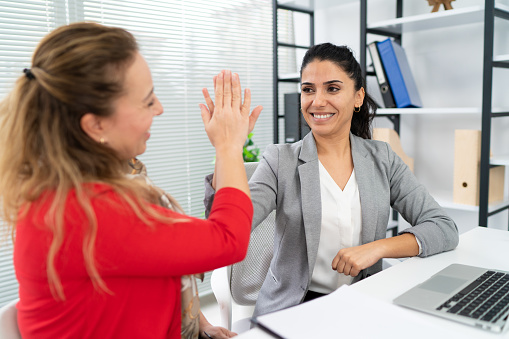 Shot of two businesswomen giving high five to each other in an office