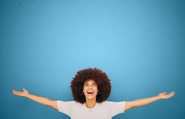 ganador, maqueta y emoción con una mujer negra en celebración en el estudio sobre un fondo azul para marketing o publicidad. motivación, espacio y colocación de productos con una mujer animando en la victoria - eufórico fotografías e imágenes de stock