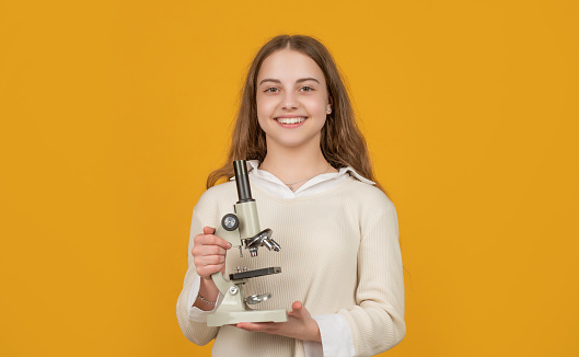 positive kid with microscope on yellow background.