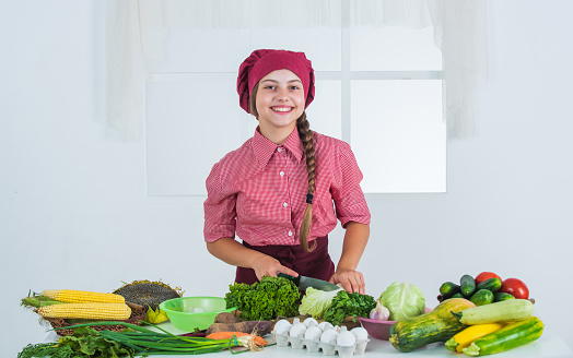 happy kid with colorful vegetables in kitchen, vitamins.