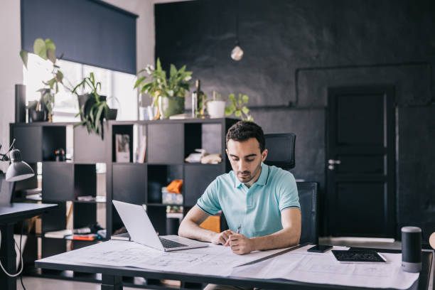 istock The architect works on the blueprint and laptop, creating detailed floor plans, elevations, and sections of the building. 1455943854
