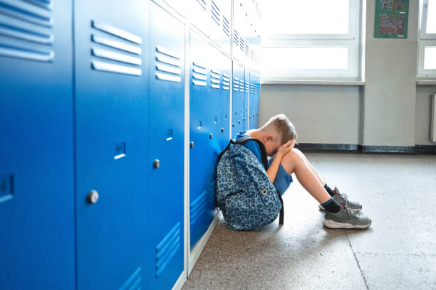 istock Sad schoolboy sitting in the school corridor 1455946146