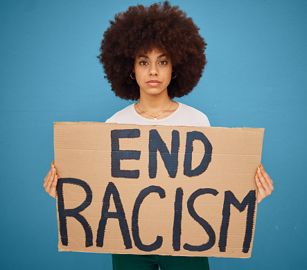 Portrait of a black woman with a stop racism banner and peacefully protesting for human rights in studio. Young afro girl with a cardboard poster fighting for race, social justice or racial equality