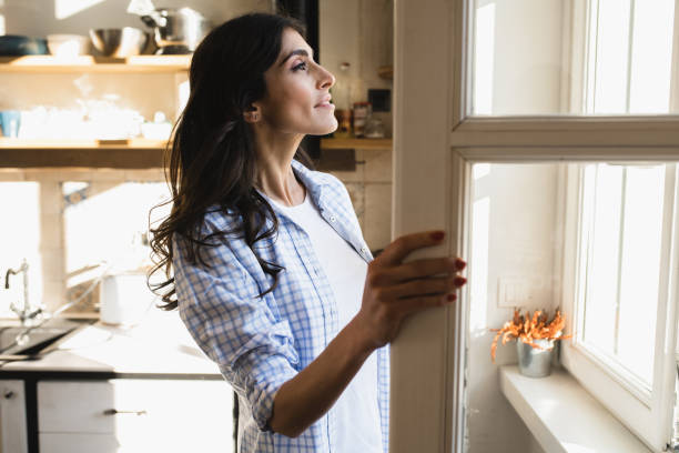 istock Young woman relaxing at home and looking through the window 1455946584