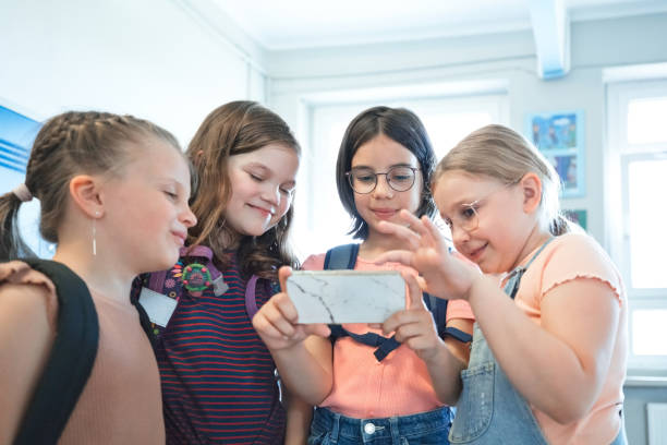 istock School girls using phone in the school corridor 1455947528