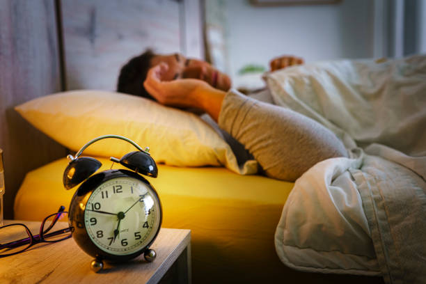 woman sleeping pacefully in bed with alarm clock on foreground - ogen dicht closeup vrouw 50 jaar stockfoto's en -beelden