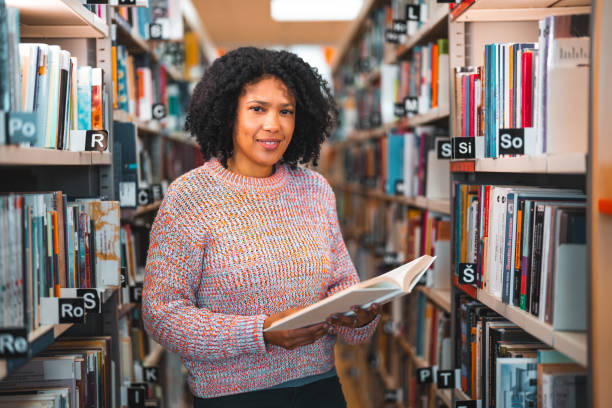 istock Latin Female Holding A Book In A Library 1455947910