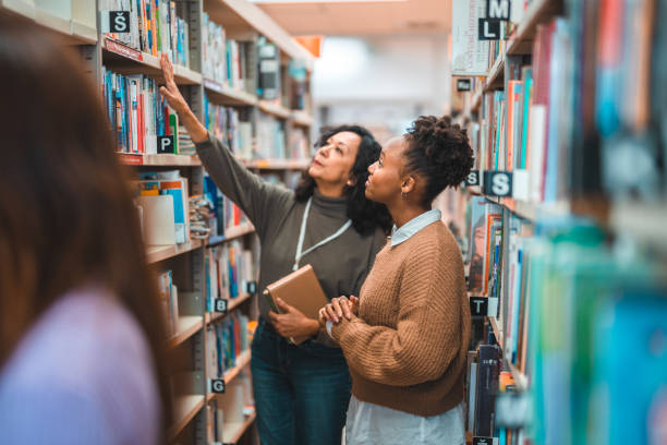 istock Hispanic Student Searching For A Book With A Librarian 1455947919