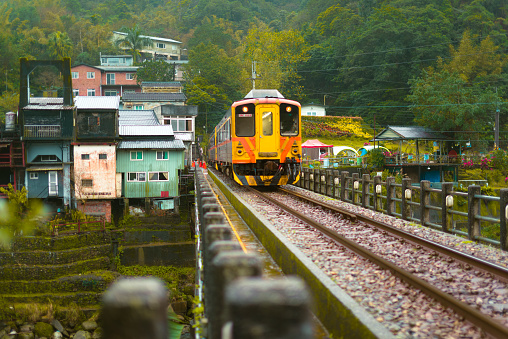 The yellow train is passing through a small village in the valley. Sandiaoling Station, Ruifang District, New Taipei City, Taiwan