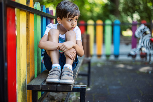 Kid sitting on a bench and feeling lonely