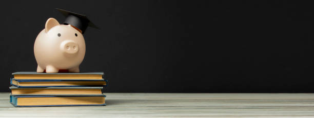 istock Piggy bank and book. College fees saving concept, copy space for text 1455952076