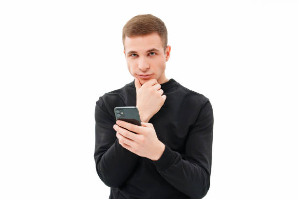 istock a pensive man in black with a smartphone in his hands on a white background. 1455952096