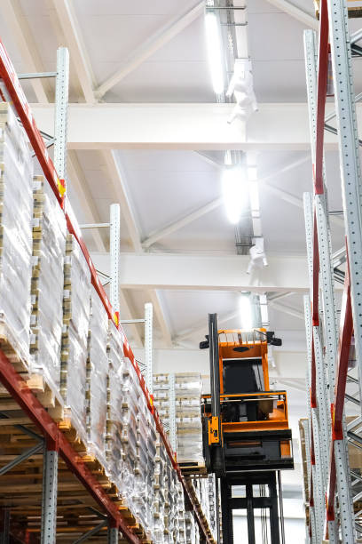 istock Narrow aisle high-rise stacker. Reach truck with raised cab. High height stacker loader in a industrial warehouse building with rows of racks. 1455953247