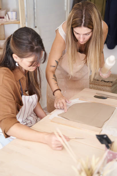istock Women wearing aprons in a ceramics workshop creating clay pieces. 1455954980